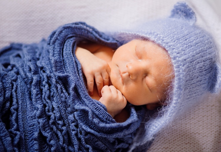 Free Photo child in blue hat and knitted scarf sleeps on white pillow 