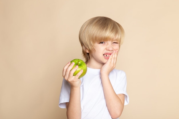 child boy cute holding green apple in white t-shirt on pink