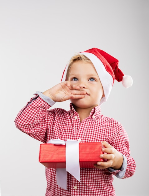 Child covering her mouth with one hand and in the other a gift