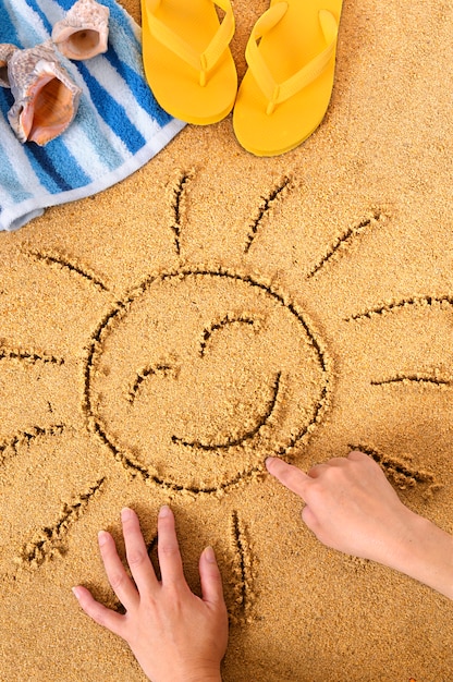 Free photo child drawing a sun in the sand