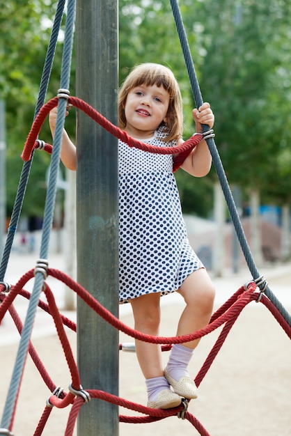 child in dress climbing at ropes