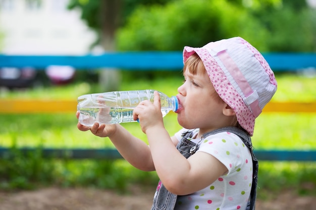 child drinks from plastic bottle