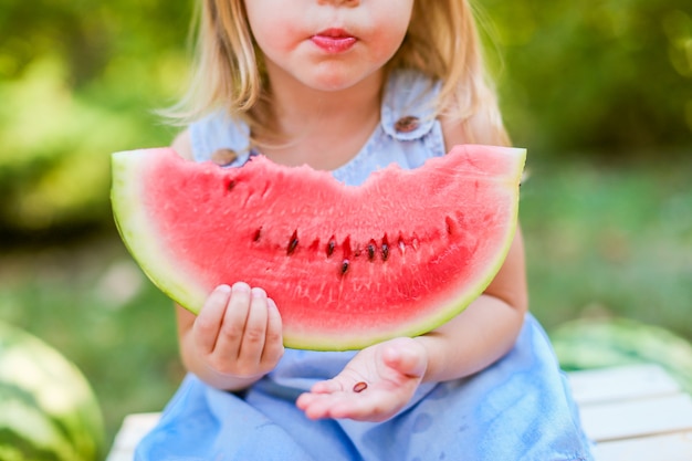 Child eating watermelon in the garden. kids eat fruit outdoors. healthy snack for children. Premium Photo