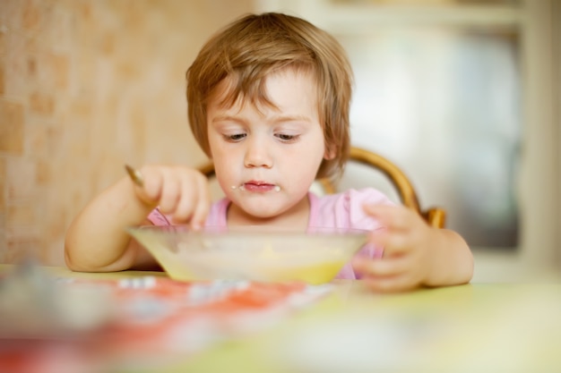 Бесплатное фото Ребенок ест с ложкой в ​​домашних условиях