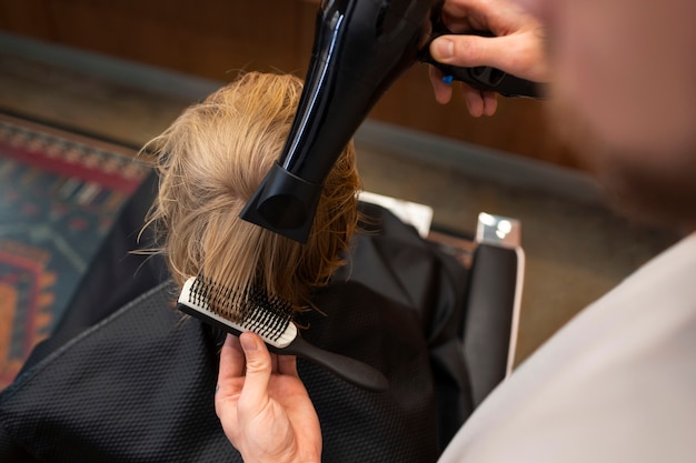 Foto gratuita bambino che si fa soffiare i capelli al salone