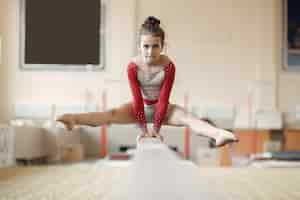 Free photo child gymnastics balance beam.  girl gymnast athlete during an exercise horizontal bar in gymnastics competitions.