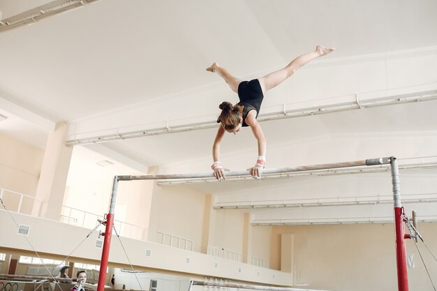 子供の体操平均台。体操競技の運動鉄棒中の女の子の体操選手。