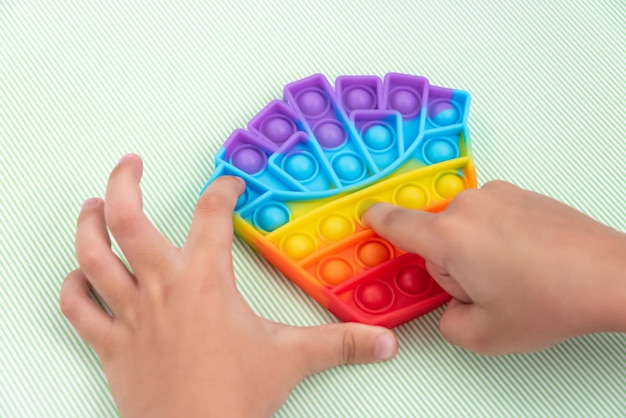 Детская рука играет с игрушкой pop it