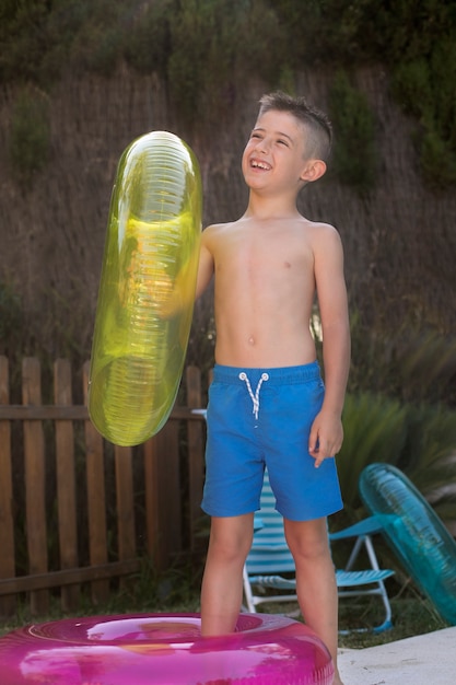 Foto gratuita bambino che si diverte con galleggiante a bordo piscina