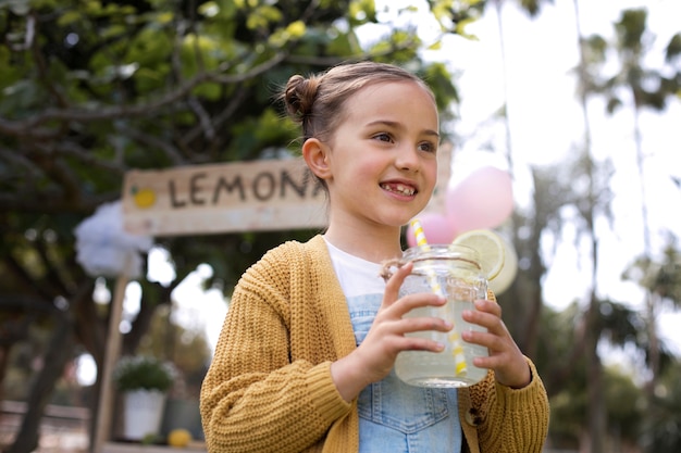 Foto gratuita bambino che ha un chiosco di limonata