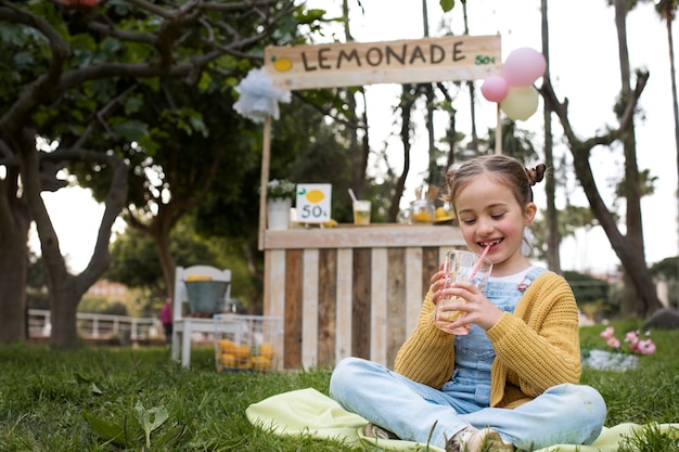 Foto gratuita bambino che ha un chiosco di limonata