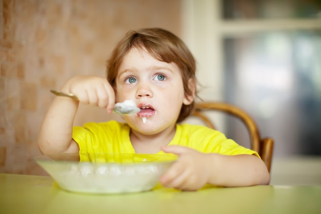 Free photo child himself eats dairy  with spoon