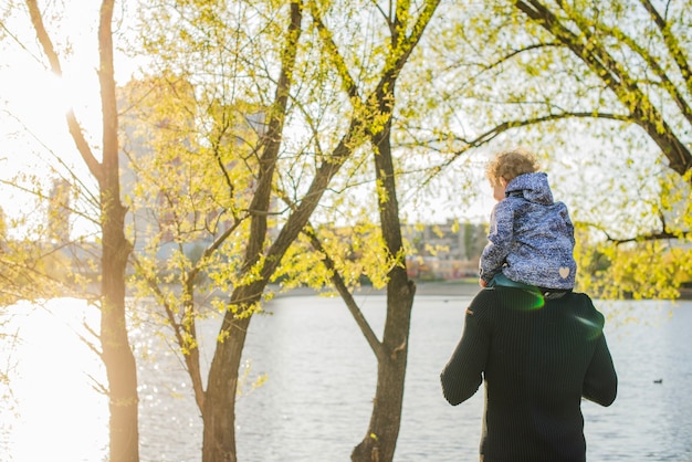 Foto gratuita bambino sulle spalle di suo padre che godono della natura