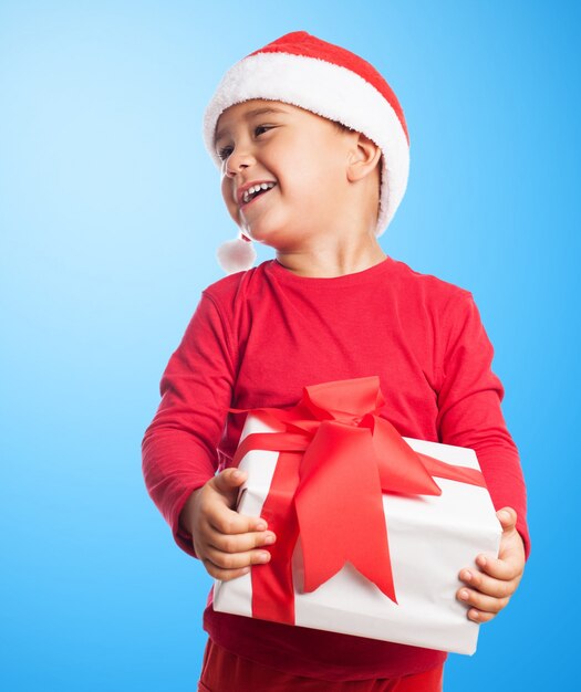 Foto gratuita bambino in possesso di un regalo bianco in uno sfondo blu