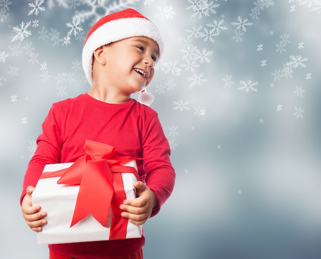 Child holding a white gift in a snowflakes background