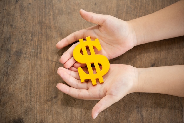 Child holding yellow dollar sign