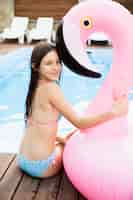 Free photo child hugging flamingo floater from behind