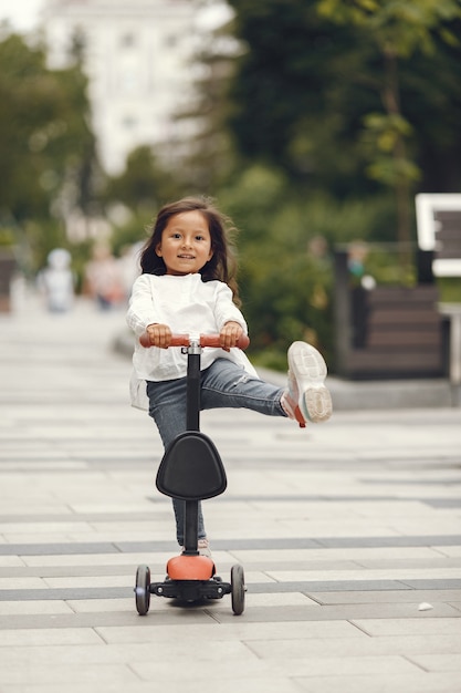 Child on kick scooter in park. Kids learn to skate roller board. Little girl skating on sunny summer day.