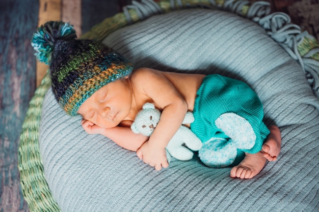 Child in knitted hat sleeps on large blue pillow 