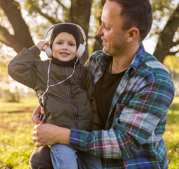 Foto gratuita bambino che ascolta la musica e che è tenuto da padre