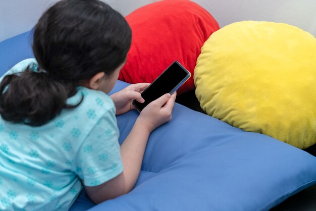 ベッド​に​横​に​なっている​子供​は​、​リラックスプレイゲーム​や​ソーシャルネットワーク​に​スマート​フォン​を​使用します