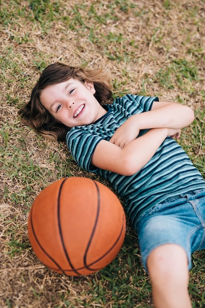 Бесплатное фото Ребенок лежал в траве с мячом