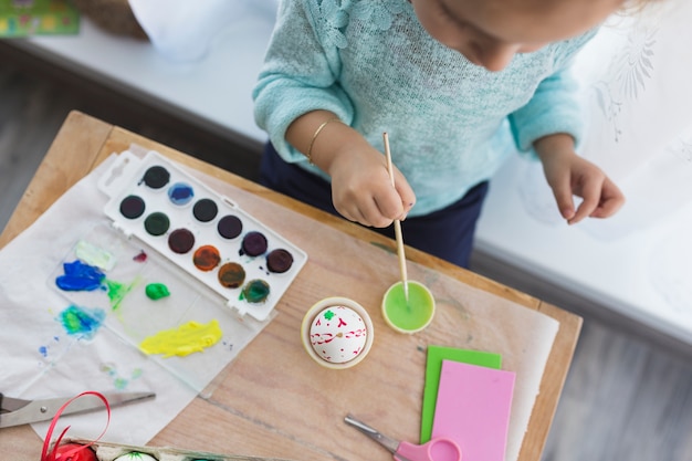 Child mixing paint for egg