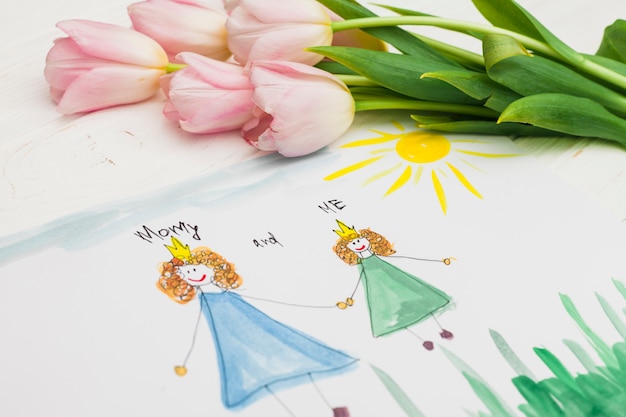 Child and mother drawing and flowers on table