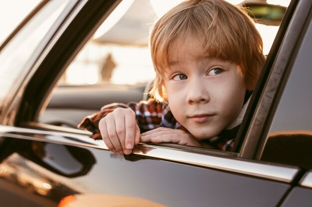 Child peeking his head out the window of a car while on road trip