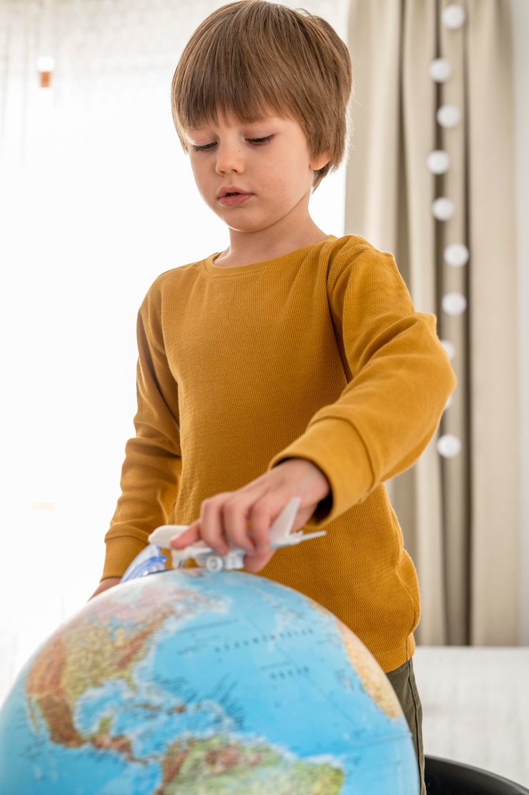 Free Photo child  playing with airplane figurine and globe