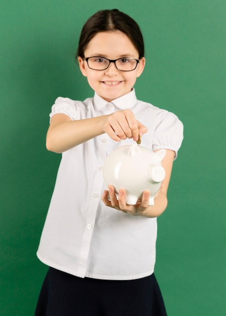 Free photo child putting coin in piggy bank