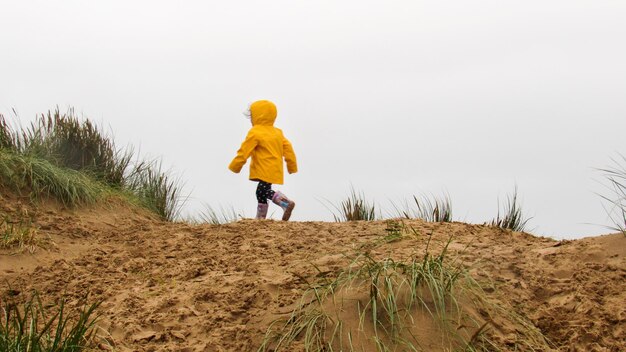 英国の海の近くのレインコートを着た子供