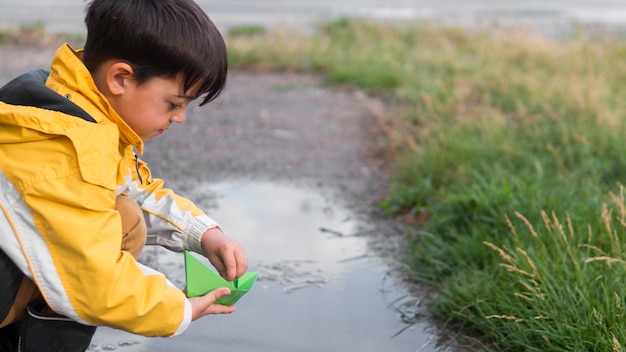 Foto gratuita bambino in impermeabile che gioca nel lago