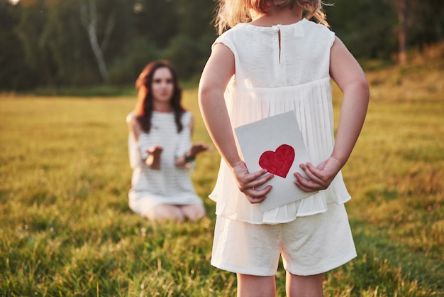 子供の娘は母親を祝福し、彼女にはがきを渡します。