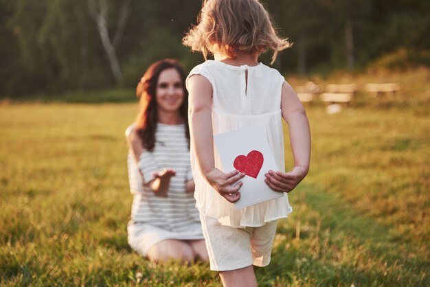 The child's daughter congratulates her mother and gives her a postcard.