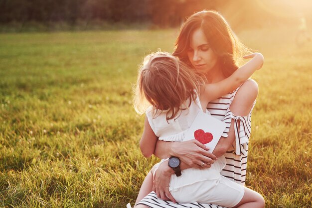 子供の娘は母親を祝福し、彼女にはがきを渡します。