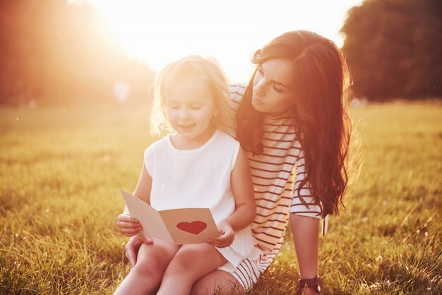 子供の娘は母親を祝福し、彼女にはがきを渡します。