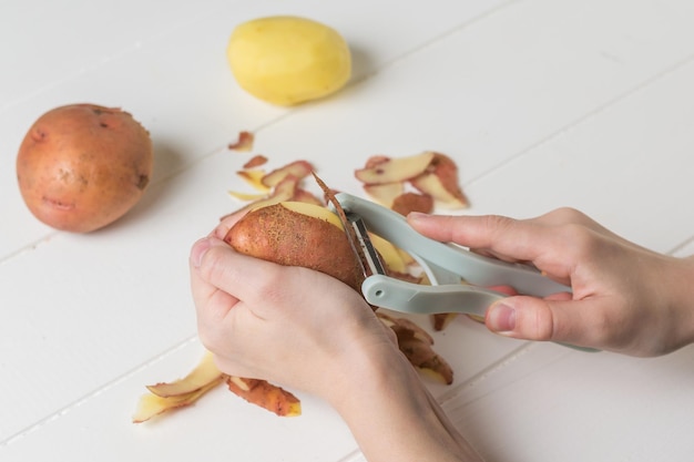 The child's hands perform peeling potatoes using a vegetable peeler. speciale quipment f or c leaning vegetables .