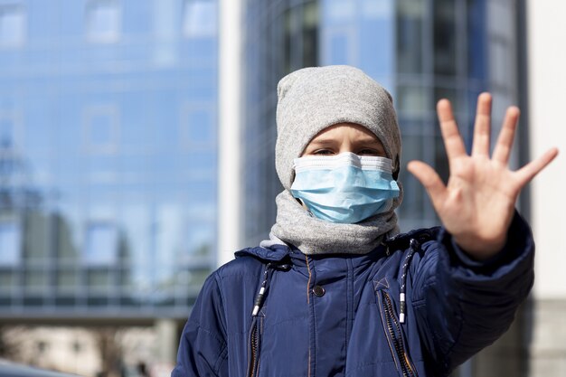 外の医療マスクを着用しながら手を示す子