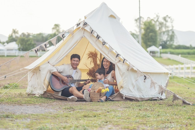 キャンプで笑顔の家族と一緒に歌う子。田舎でキャンプを楽しむ家族。