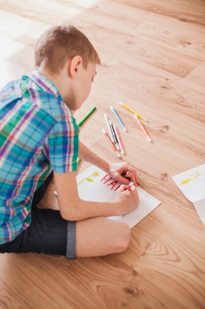 Ребенок сидит на полу и рисует на день матери