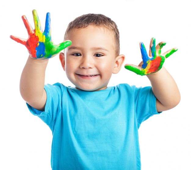 Child smiling with hands full of paint