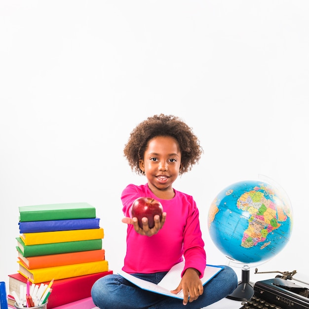 Free photo child studying and holding apple in studio