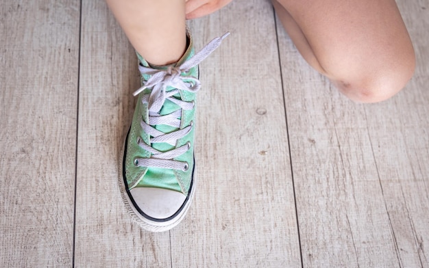 Foto gratuita il bambino lega con successo le scarpe da vicino sui piedi