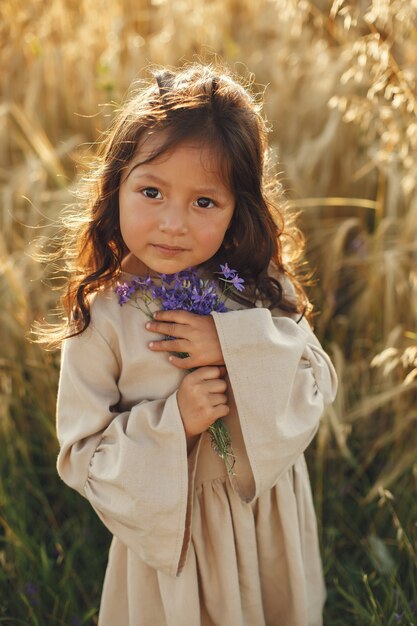 Child in a summer field. Little girl in a cute brown dress.