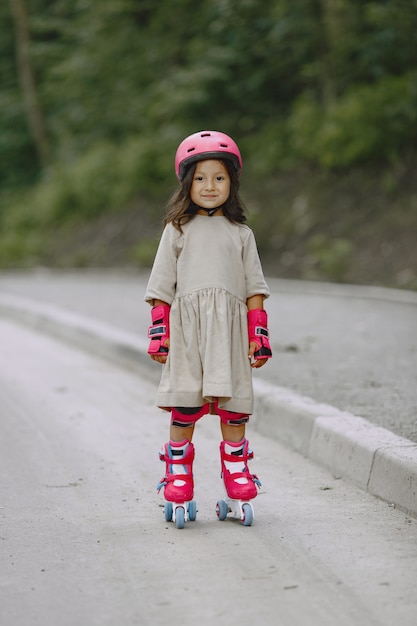 Bambino in un parco estivo. ragazzo con un casco rosa. bambina con un rullo.