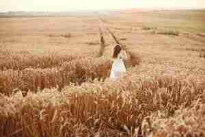 Free photo child in a summer wheat field. little girl in a cute white dress.