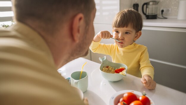 Child taking cereals from the bowl and eats