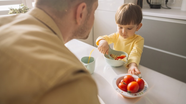 Child taking cereals from the bowl with spoon