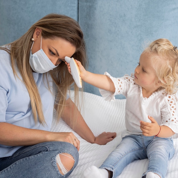 Child taking mother's temperature with thermometer